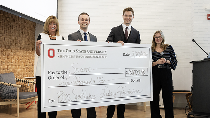 Four people on stage hold a large check from Ohio State Keenan Center.