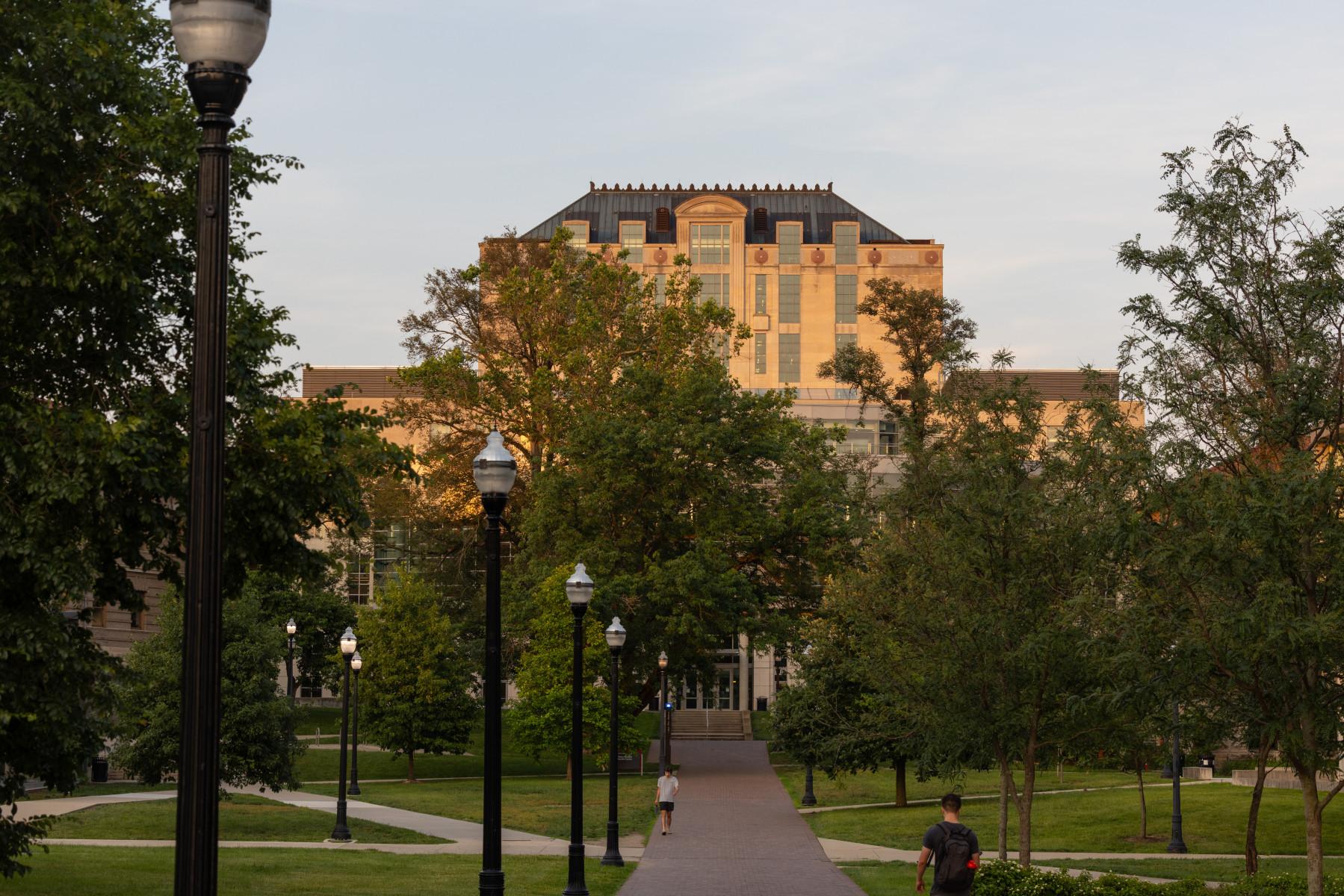 Thompson Library with a path and light posts on the oval. Campus on a summer evening.