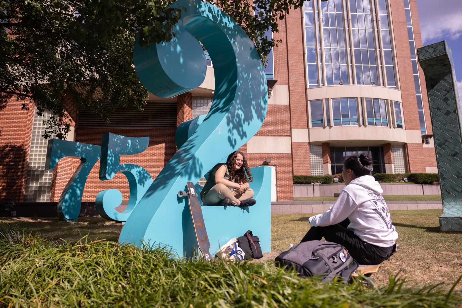 Two students talk among Barbara Grygutis' "Garden of Constants" sculptures outside of Dreese Laboratories.